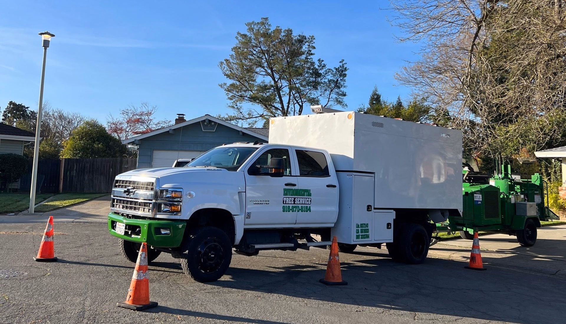 Environmental Tree Service chip truck and chipper set up with cones on a residential street