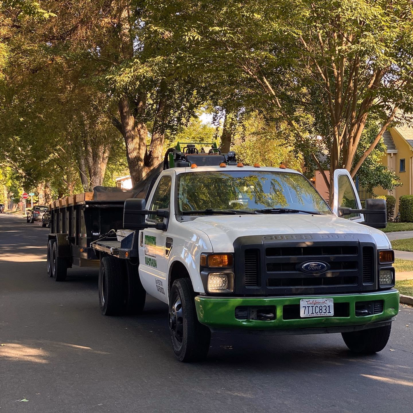 Environmental Tree Service truck and trailer on a tree-lined street